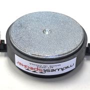 Round metal buzzer or speaker transducer with a black plastic base and two solder terminals on opposite sides, used in electronics projects